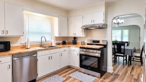 A modern kitchen with white cabinets, stainless steel appliances, and a wooden countertop. - Cozy 2 Bedroom Monthly (Hot Springs)