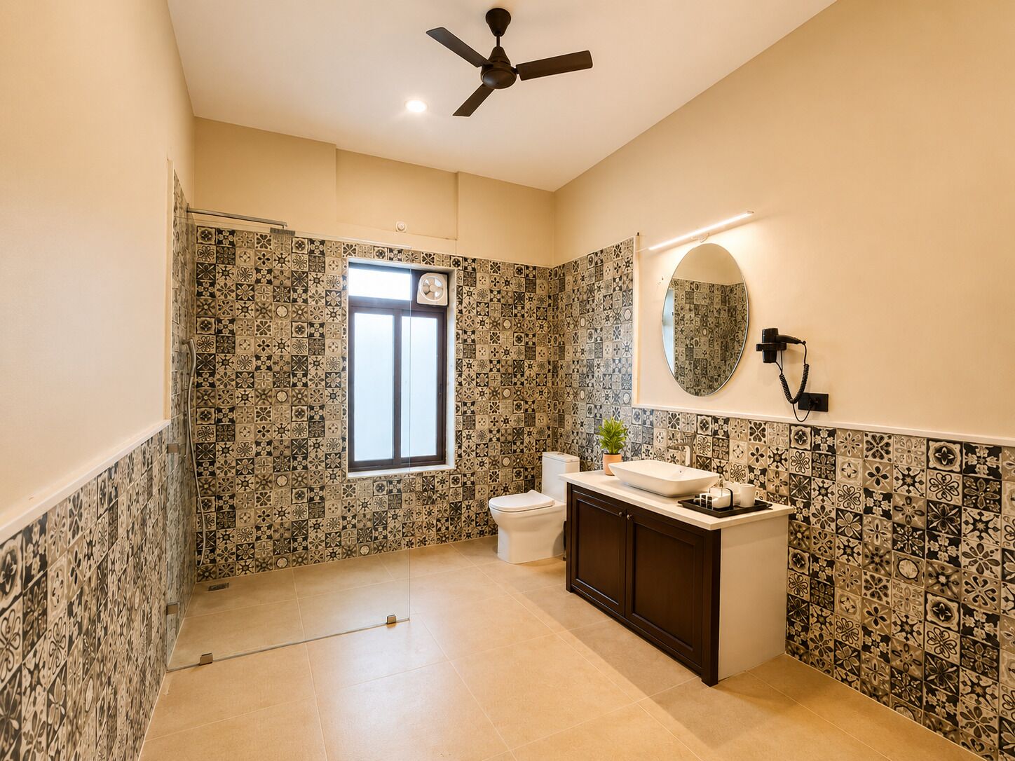 A bathroom with patterned tiles, a toilet, a sink with a mirror, and a ceiling fan.