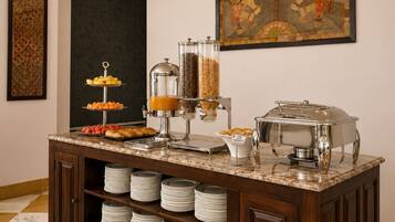 A buffet setup with a marble countertop, a coffee station, and a decorative painting on the wall.