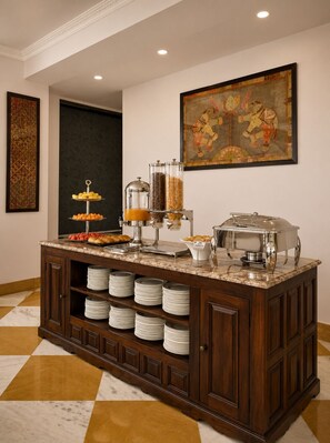 A buffet setup with a marble countertop, a coffee station, and a decorative painting on the wall. - Barliyas Heritage Boutique Hotel (Udaipur)