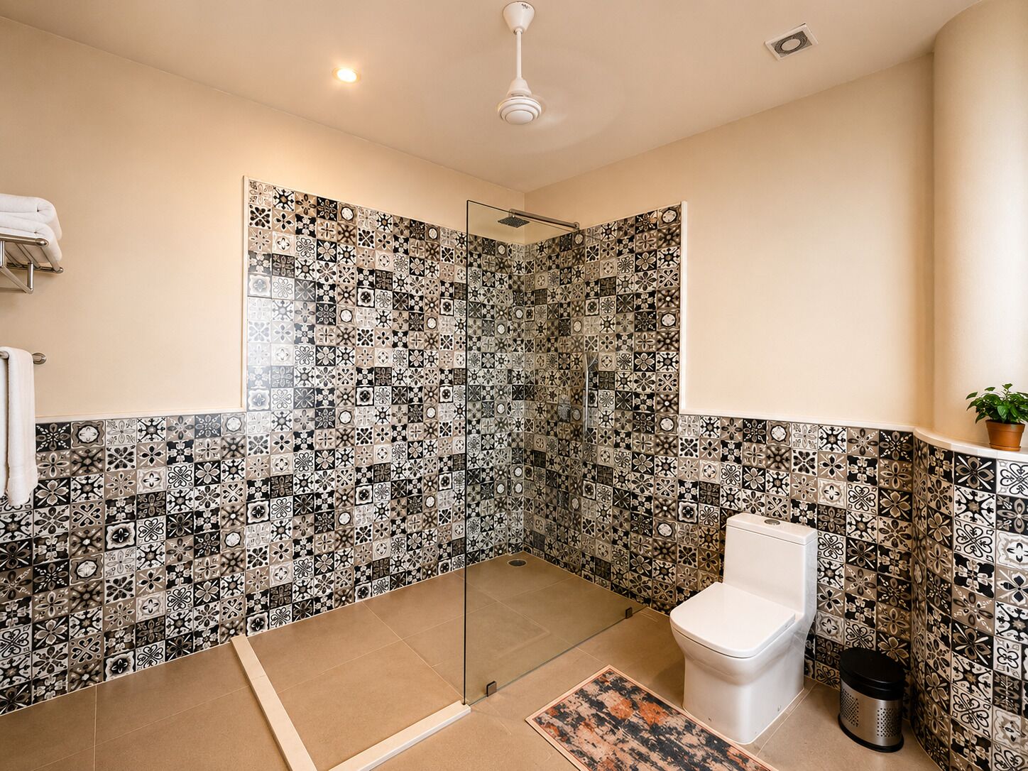 Baño con ducha, inodoro y pared de baldosas estampadas.