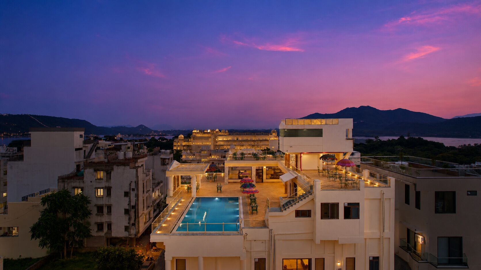 Un hotel con piscina, mobiliario exterior y vistas a las montañas.