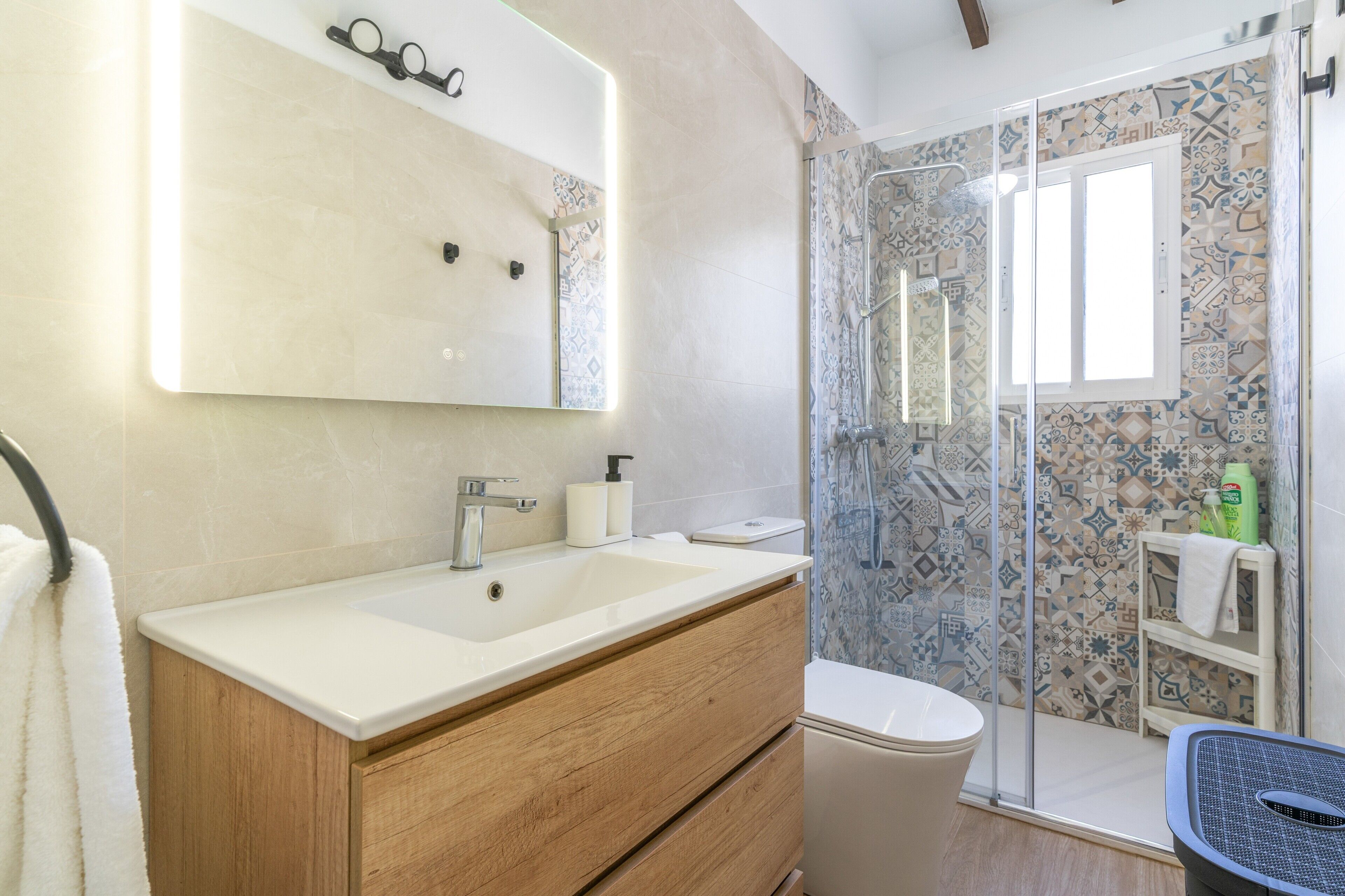 Ein Badezimmer mit großem Spiegel, Waschbecken, Toilette und Duschbereich.