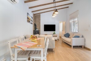Un espacio habitable moderno con comedor, sofá, televisor y chimenea.