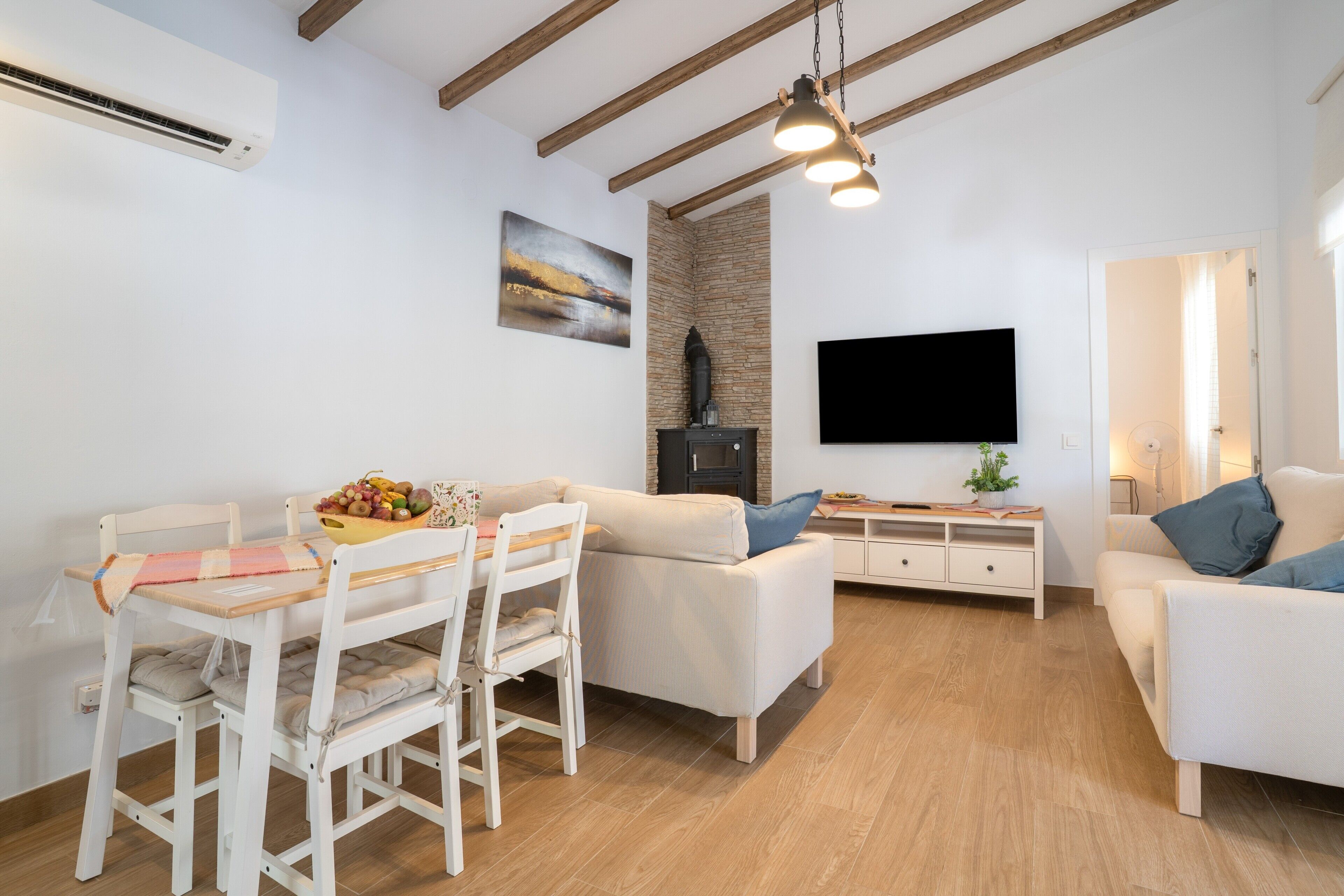 Ein modernes Wohnzimmer mit Essbereich, Holzboden, einem Flachbildfernseher und einem Kamin aus Stein.