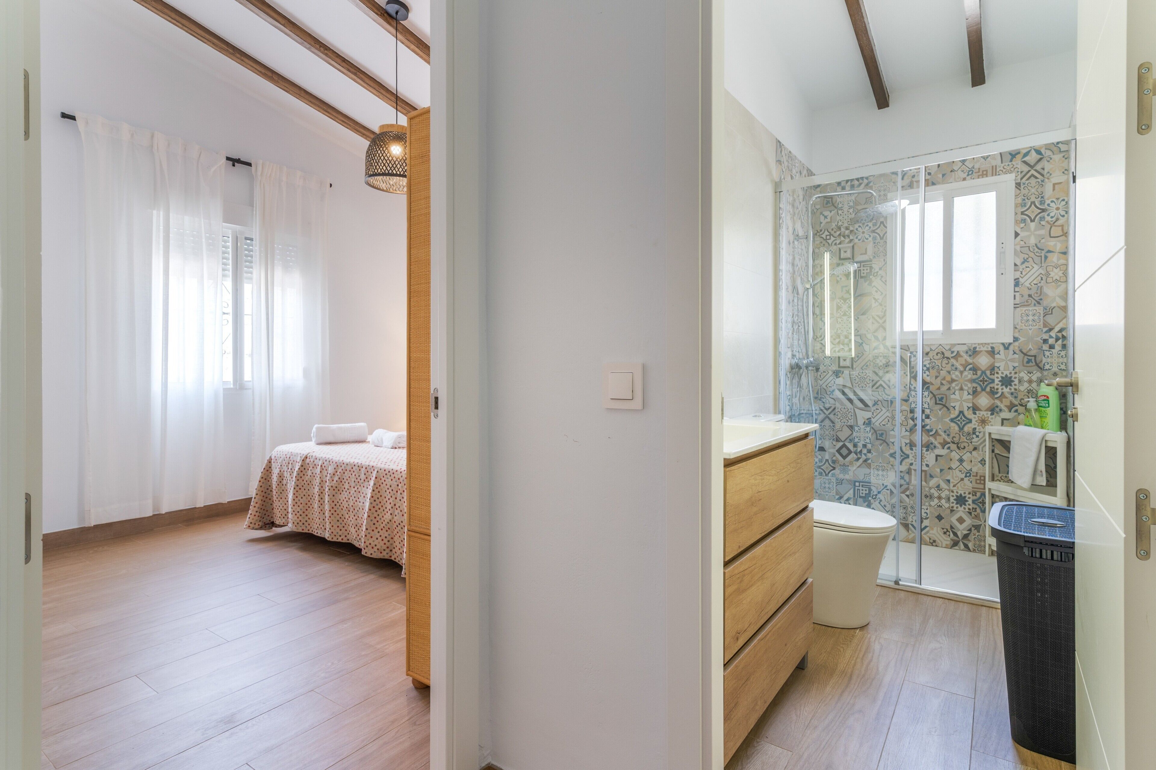 A bedroom with a bed and a bathroom with a shower and toilet.
