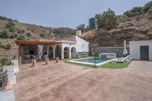 Una villa con piscina, mobiliario de exterior y un muro de piedra.