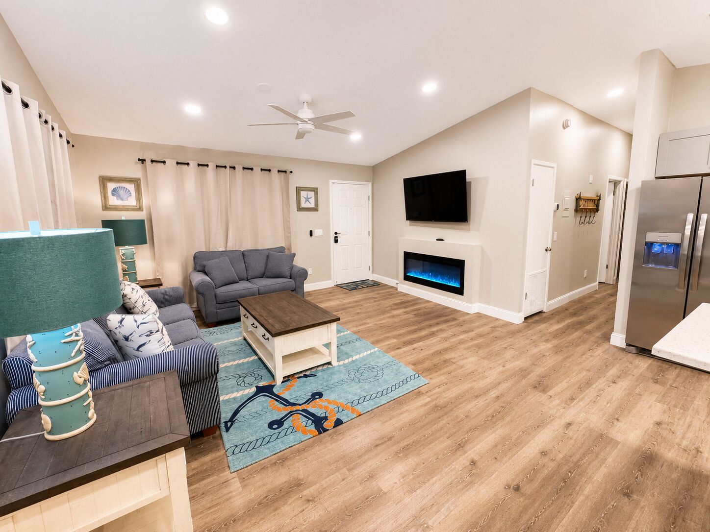 A living room with a sofa, a coffee table, a fireplace, a TV, and a refrigerator.