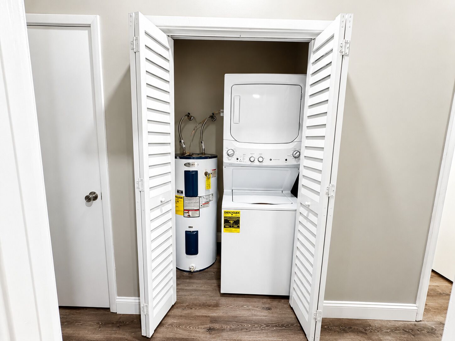 A laundry room with a washer and dryer, a water heater, and a door leading to another room.