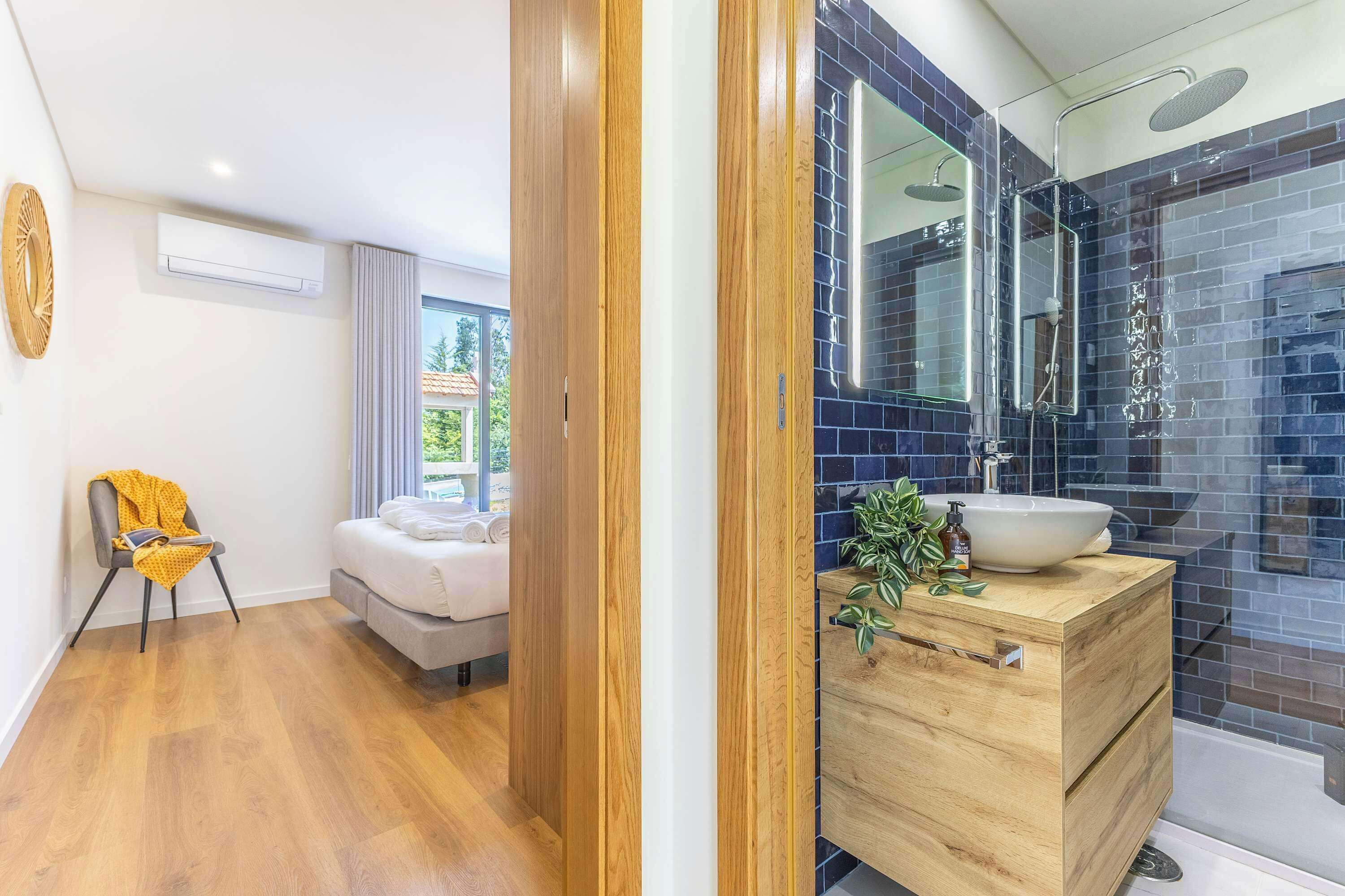 A modern bathroom with a large mirror, a sink, and a shower.