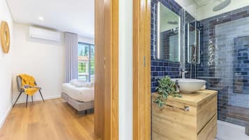 A modern bathroom with a large mirror, a sink, and a shower.