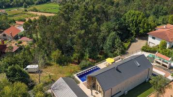 Zona residencial con una casa grande que cuenta con una piscina, rodeada de vegetación y colinas al fondo.