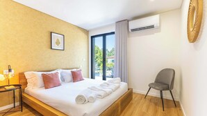 Ein Hotelzimmer mit einem Bett, einem Sessel, einem Nachttisch mit Lampe und einer Klimaanlage.