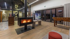 Ein modernes Interieur mit Kaminofen, Kicker und großem Fenster mit Außenblick.