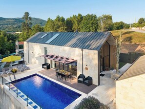Un edificio moderno con piscina, area salotto esterna e vista sul paesaggio circostante.