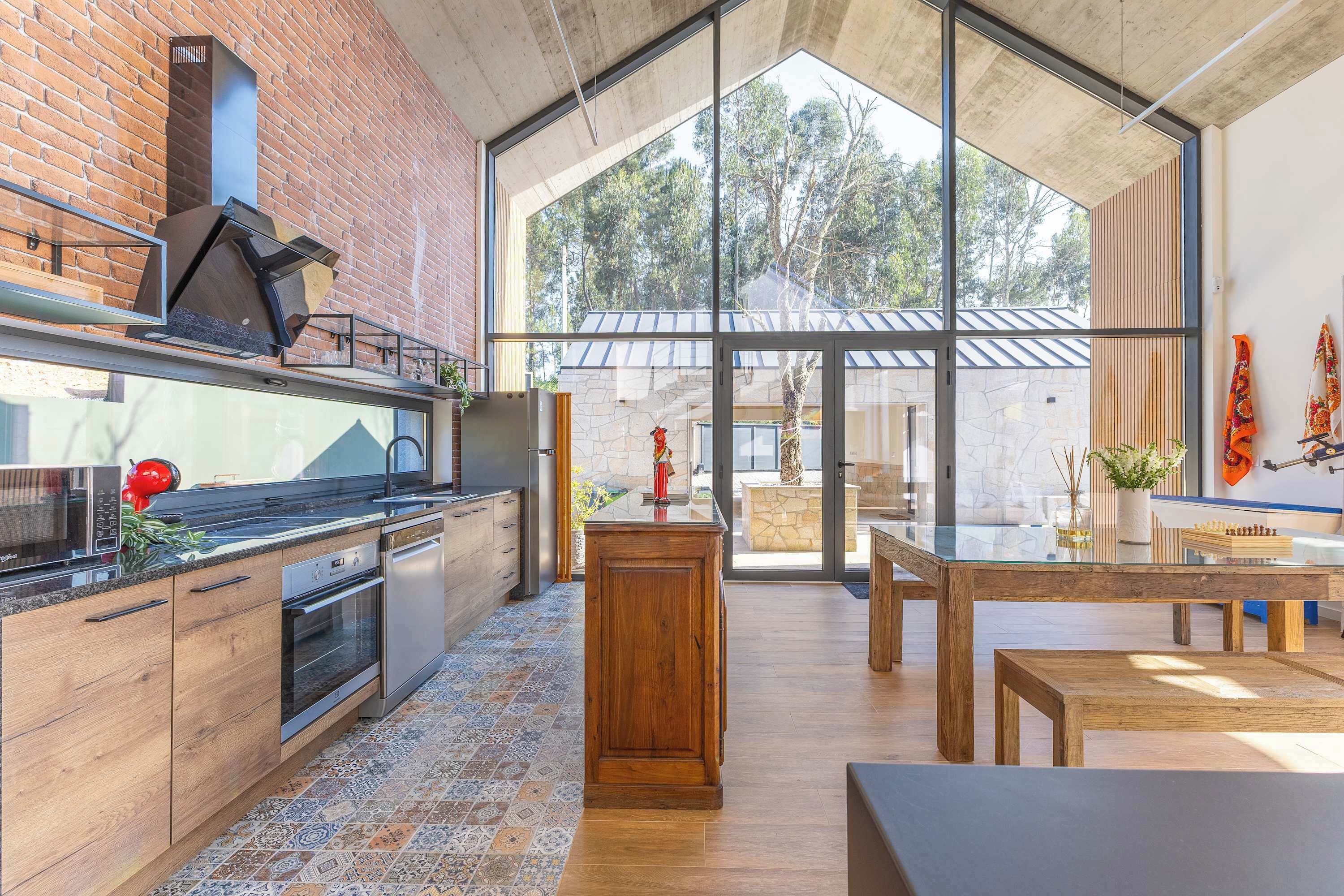 Una cocina moderna con pared de ladrillo, ventanas grandes y vistas al exterior.