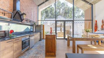 Una cocina moderna con pared de ladrillo, ventanas grandes y vistas al exterior.