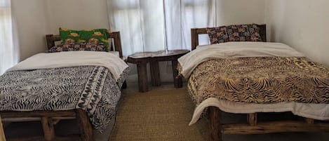 A room with two wooden beds, a small round table, and a woven rug.