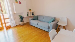 A modern living room with a light blue sofa, a white chair, a wooden floor, and a white cabinet with shelves. - La Casa di Greta - One Bedroom Apartment, Sleeps 4 (Peschiera del Garda)