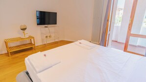 A hotel room with a bed, a TV, a wooden bench, and a glass table. - La Casa di Greta - One Bedroom Apartment, Sleeps 4 (Peschiera del Garda)