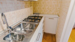 Eine Küche mit einem Gasherd, zwei Edelstahl-Spülen und einem weißen Schrank.