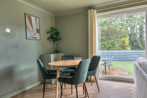 Ein Essbereich mit Tisch und Stühlen, einer Topfpflanze und Blick ins Freie.