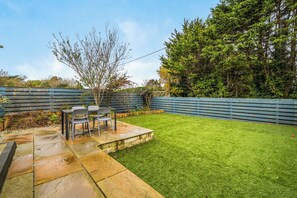 A backyard with a patio area, a small tree, and a wooden fence. - 2 Bed Apartment Sleeps 4 - Pets Welcome (St Ives)