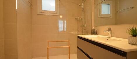 A modern bathroom with a glass shower enclosure, a vanity with a sink, and a mirror.