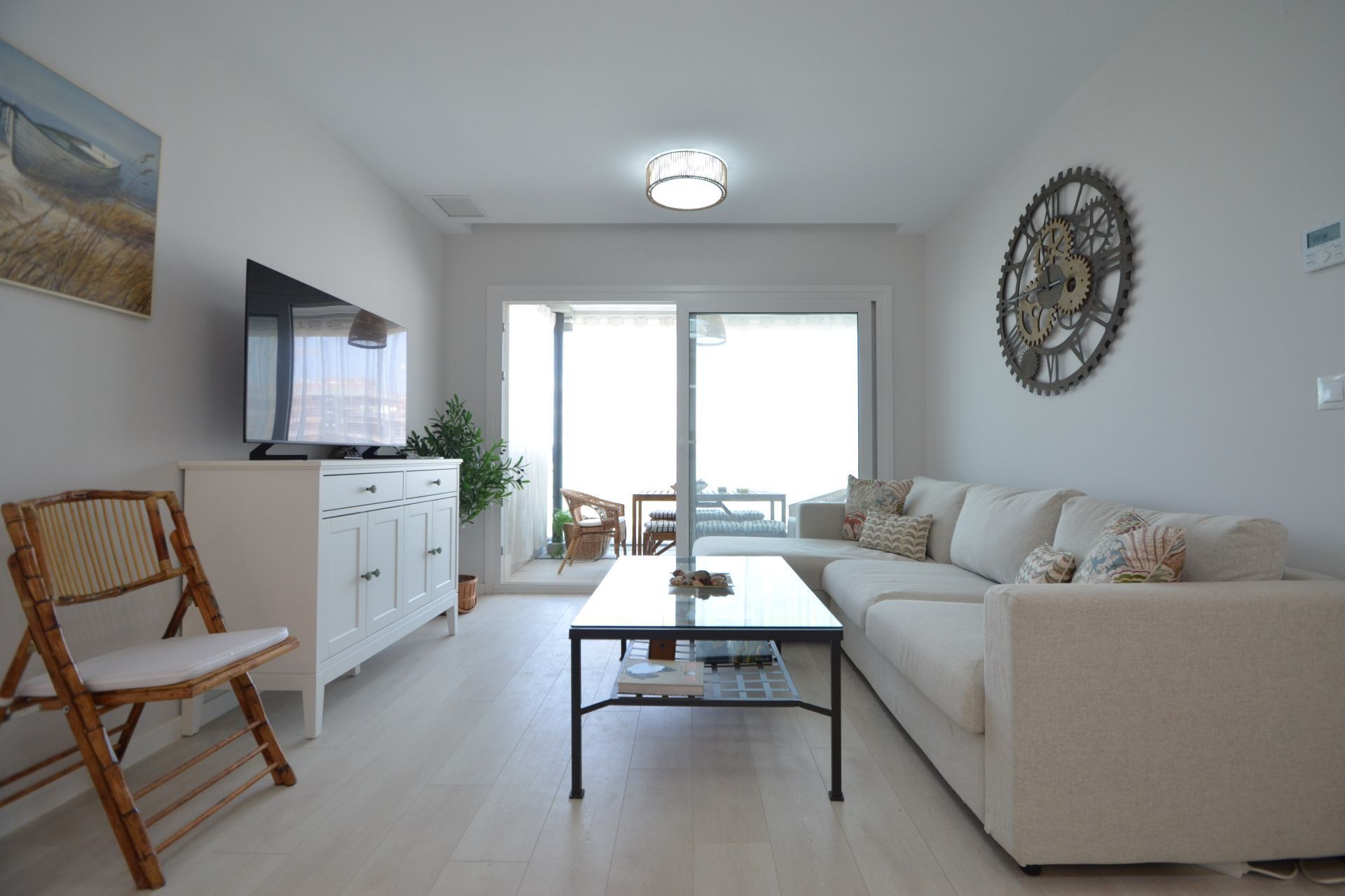 A modern living room with a sofa, a coffee table, a TV, and a decorative wall clock.