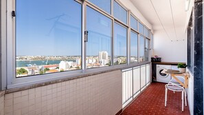 Ein Balkon mit Blick auf die Stadt, einer Waschmaschine und einem kleinen Tisch mit einer Pflanze.