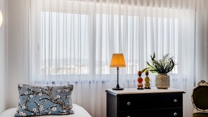 Ein Schlafzimmer mit einem Bett, einem Nachttisch, einer Lampe, Dekoration und transparenten Vorhängen.