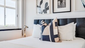 Ein Hotelzimmer mit Bett, Fenster und gerahmten Bildern an der Wand.
