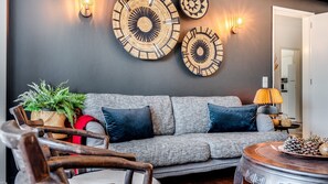 Ein modernes Wohnzimmer mit einem grauen Sofa, Wandbildern und einem Holztisch.