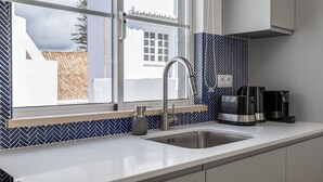 A modern kitchen with a stainless steel sink, a window with a view of buildings, and a coffee maker on the counter. - Rooftop Terrace in Tavira by LovelyStay (Tavira)