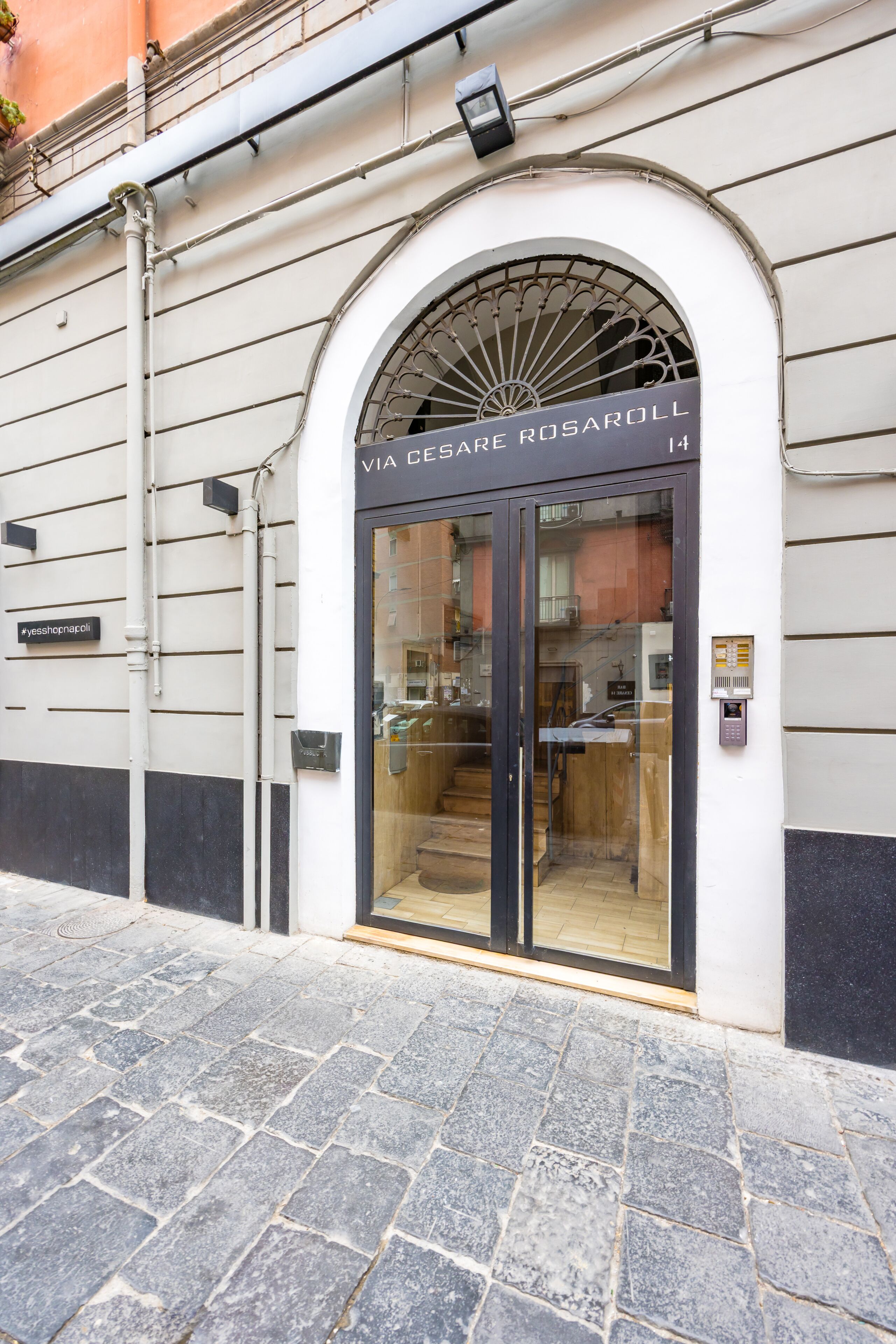 A building entrance with a glass door, a metal awning, and a sign above the door.