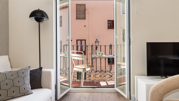 Ein offener Balkon mit Tisch, Stühlen und einem Fernseher auf einem Schrank.
