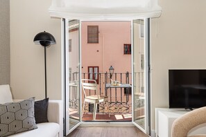 Avoin parveke, jossa on pöytä, tuoleja ja televisiotaulutelineeseen asennettu televisio.