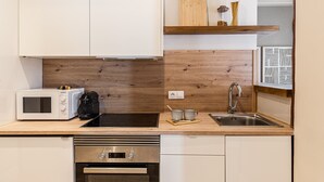 Eine moderne Küche mit Mikrowelle, Herd, Spüle und einer Holz-Spritzschutzwand.