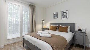 Un dormitorio moderno con una cama grande, mesitas de noche, una lámpara y obras de arte en las paredes.