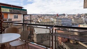 A balcony with a table and chairs, overlooking a cityscape with buildings and a dome structure. - Triple G Rooftop 102 By Dimorra  (Naples)