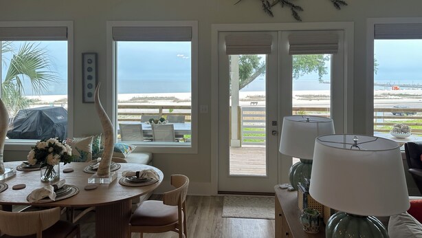 Un comedor con vista al océano, una decoración grande con forma de pez en la pared y una mesa dispuesta para cuatro personas.