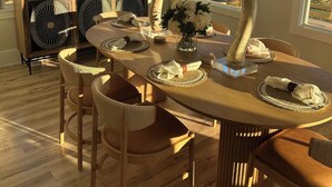 Un comedor con una mesa de madera, sillas y vista a la playa.