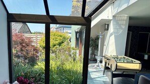 A room with a glass door leading to a garden, a foosball table, and a potted plant. - 🌿 Domaine Saint François – L'Îlot Cocooning (Saint-Hernin)