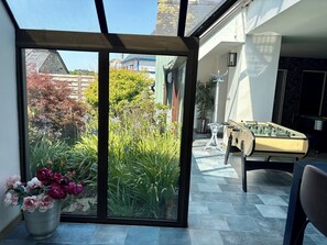 Ein Zimmer mit Glastür zu einem Garten, einem Kicker und einer Zimmerpflanze.