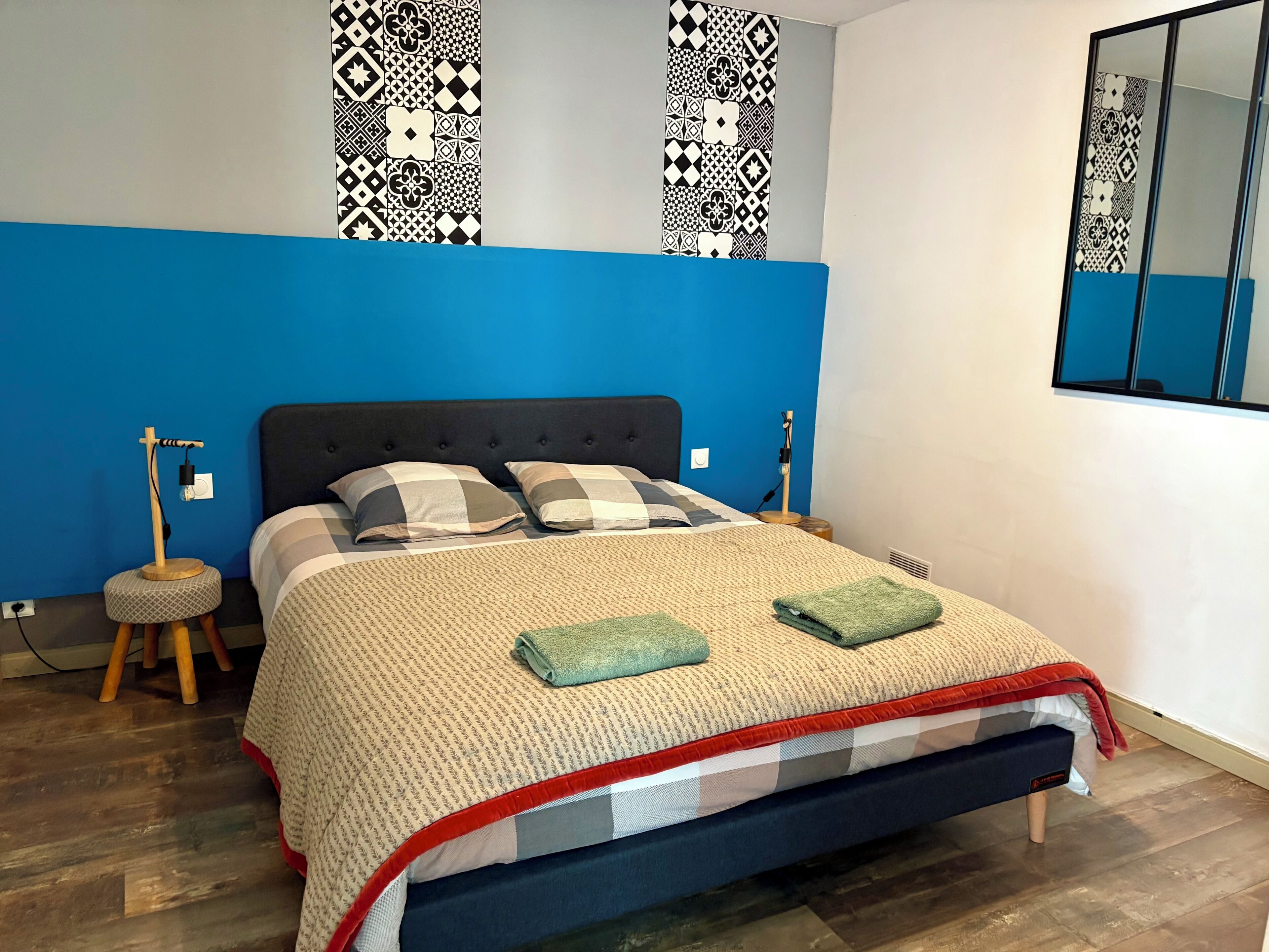 Un dormitorio con una cama, una lámpara de noche, un reloj de pared y un espejo.