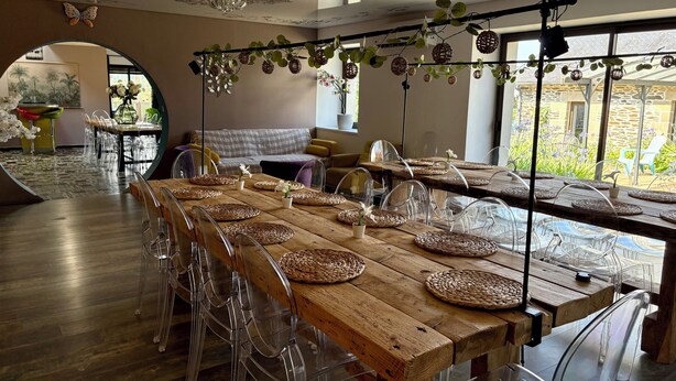 A dining area with a long wooden table, clear chairs, and woven placemats. - 🌿 Domaine Saint François – L'Îlot Cocooning (Saint-Hernin)