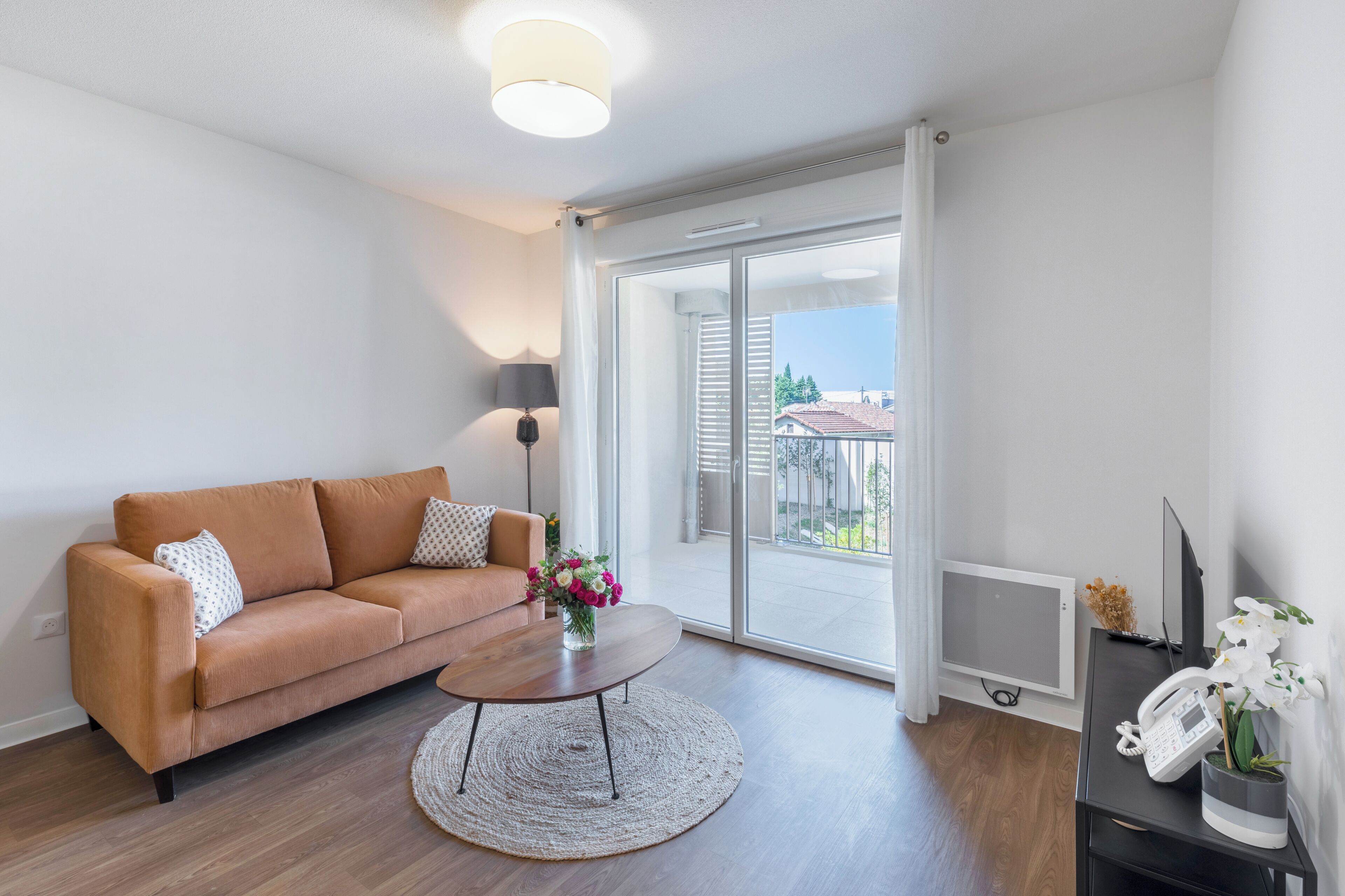 Ein modernes Wohnzimmer mit einer Couch, einem Couchtisch und Blick ins Freie durch eine Schiebetür.