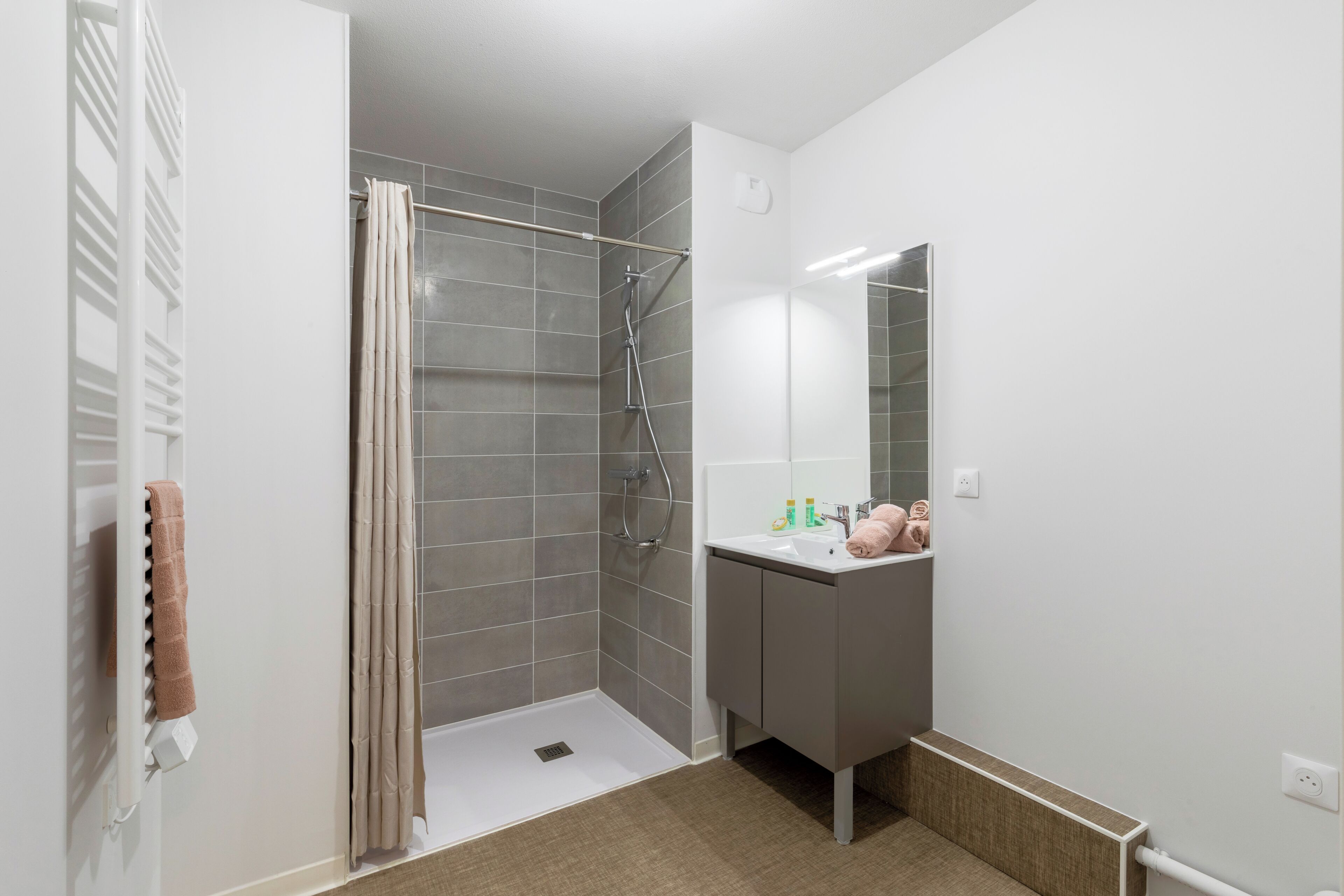 A modern bathroom with a shower, a sink, and a mirror.