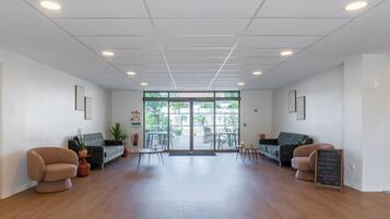A spacious lobby with a wooden floor, two sofas, a small table, and a glass door leading outside.