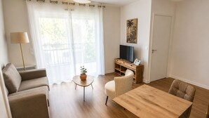 A modern living room with a sofa, a coffee table, a dining table, and a TV stand.